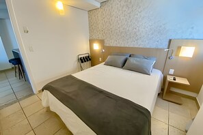 Una habitación de hotel con cama, mesitas de noche, una silla y un escritorio.