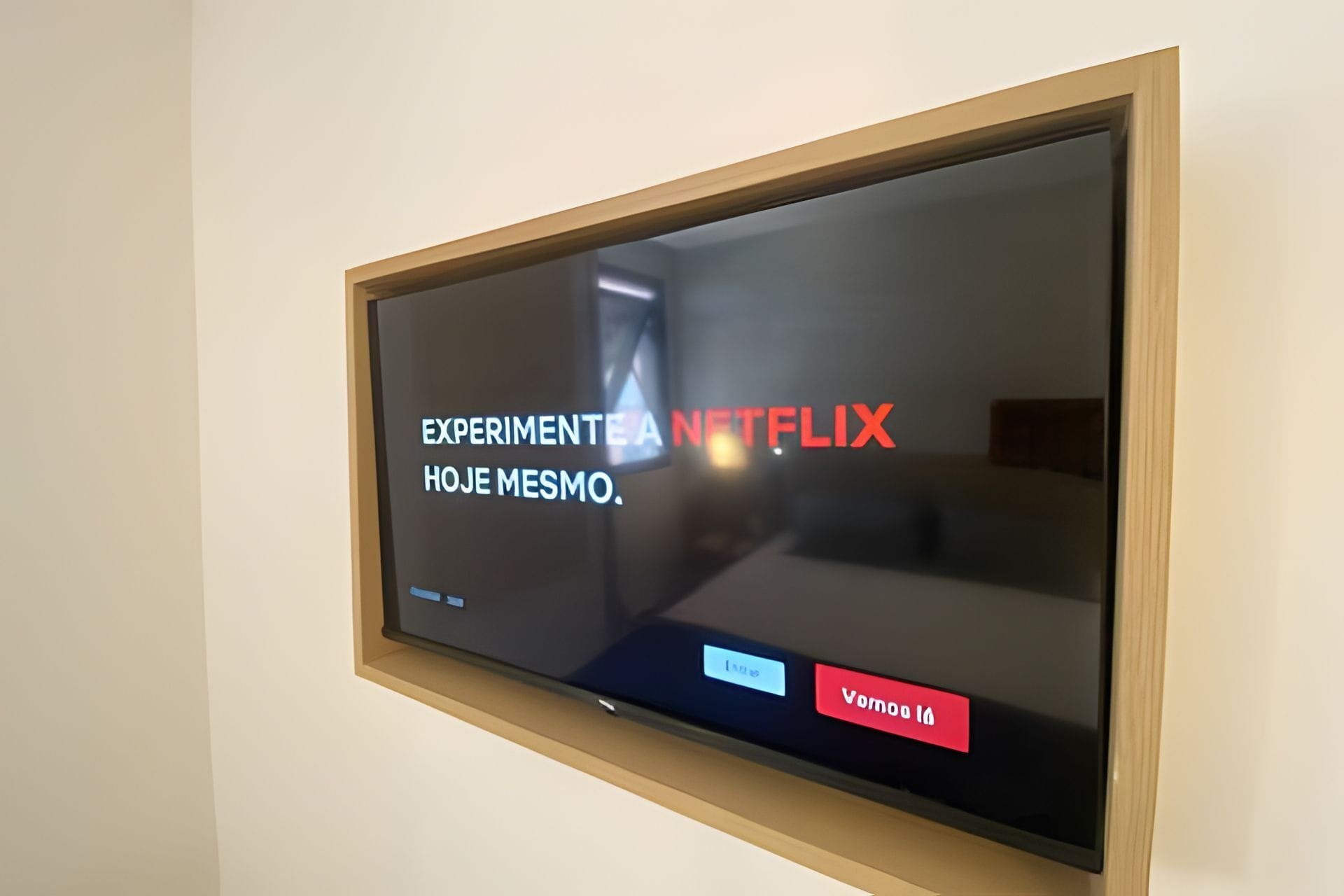 A television mounted on a wall displaying a Netflix interface with the text "EXPERIMENTE TEA HOJE MESMO."