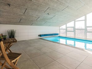 Ein Innenpool mit gefliestem Boden, einer Holzbank und einem Blumentopf.