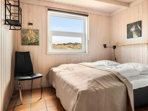 Ein Zimmer mit Bett, Sessel, Fenster mit Blick und Wandlampe.