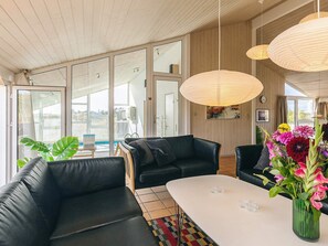 A modern living room with a black leather sofa, a white table, and a vase of flowers. - 5 Star Holiday Home in Hjorring (Hjørring)