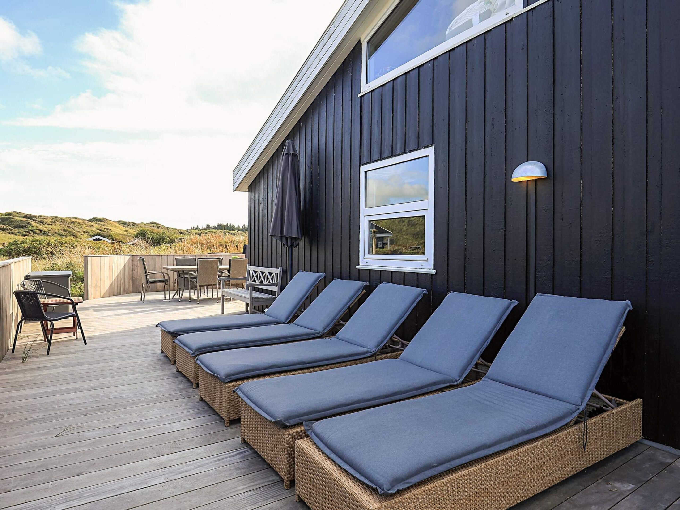 A deck with four lounge chairs and a table, overlooking a natural landscape.