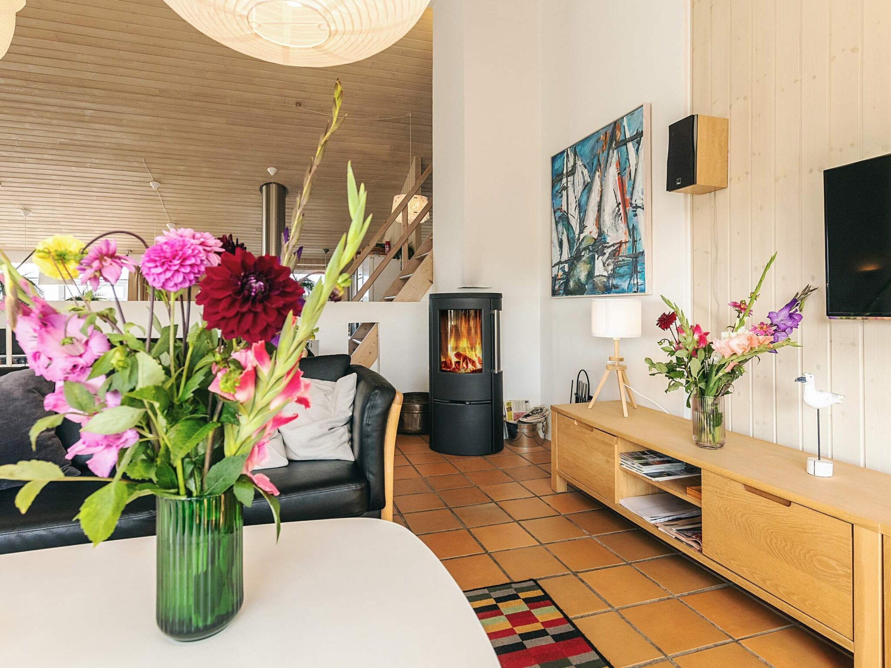 Ein modernes Wohnzimmer mit Kamin, einer Couch, einem Couchtisch und einer Blumenvase.