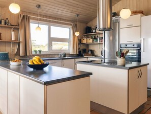 A modern kitchen with a central island, stainless steel appliances, and a view of the outdoors. - 5 Star Holiday Home in Hjorring (Hjørring)