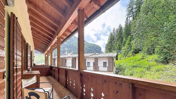 Ein Holzbalkon mit Blick auf einen Berg und einen Wald.