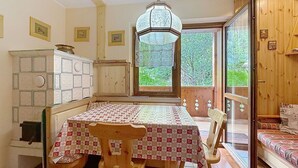 Eine gemütliche Küche mit Esstisch, Stühlen, einer Pendelleuchte und Blick auf Grünflächen.