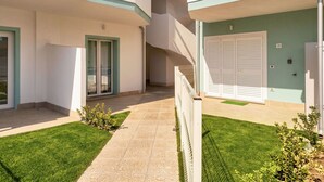 Un edifici residencial amb una zona exterior coberta, una escala i una porta amb un número.