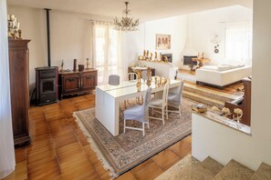 A spacious living area with a dining table, chairs, a fireplace, and a chandelier.