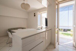 A modern bedroom with a large bed, a desk with a computer, and a view of the outdoors.