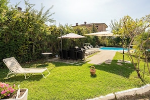 A backyard with a swimming pool, outdoor furniture, and a garden.