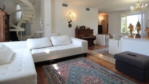 Ein modernes Wohnzimmer mit einem weißen Sofa, einem Klavier und einer Treppe.