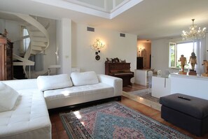 Ein modernes Wohnzimmer mit einem weißen Sofa, einem Klavier und einer Treppe.