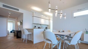 Una cocina moderna con armarios blancos, una zona de comedor con mesa y sillas, y una isla de cocina visible.