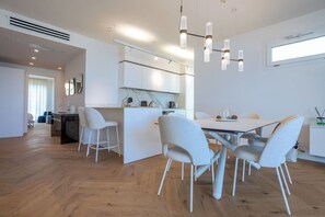Eine moderne Küche mit weißen Schränken, einem Essbereich mit Tisch und Stühlen sowie einer sichtbaren Kücheninsel.