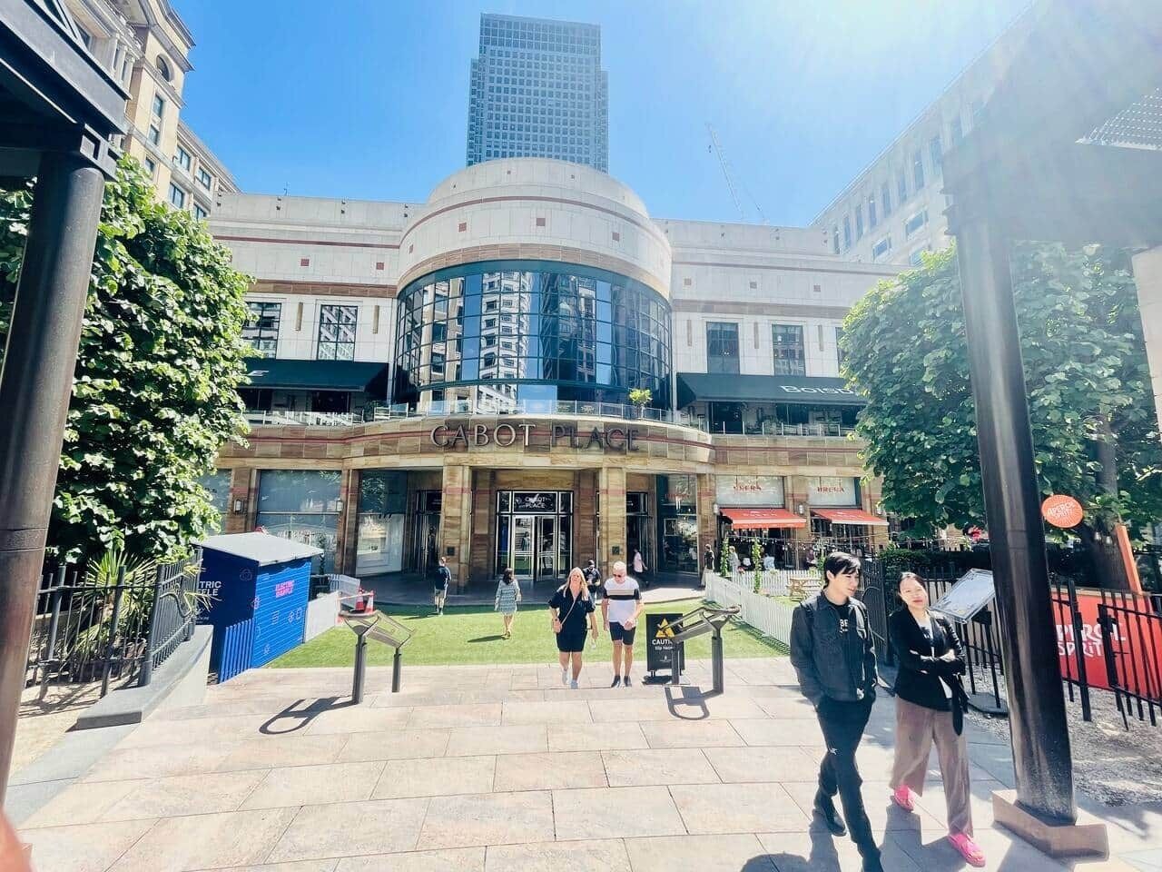 Entrada d'hotel amb façana corbada, estructura de vidre central i cel blau.
