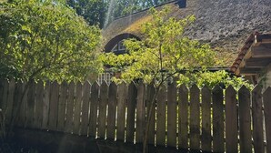 Un edificio con un tetto di paglia, una recinzione di legno e alberi sullo sfondo.