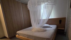 A bedroom with a bed, a canopy, a nightstand, and a wall-mounted alarm clock. - Kaz Détente, a 3-bedroom house with a hot tub, just 5 minutes from the beach! (Pointe-Noire)