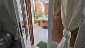 An open door leading to a covered outdoor area with a wooden deck and a pool. - Kaz Détente, a 3-bedroom house with a hot tub, just 5 minutes from the beach! (Pointe-Noire)