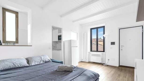 Ein Schlafzimmer mit Bett, Kleiderschrank, Heizkörper und Fenster.