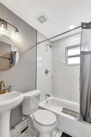 Ein Badezimmer mit Toilette, Waschbecken, Badewanne und Dusche.