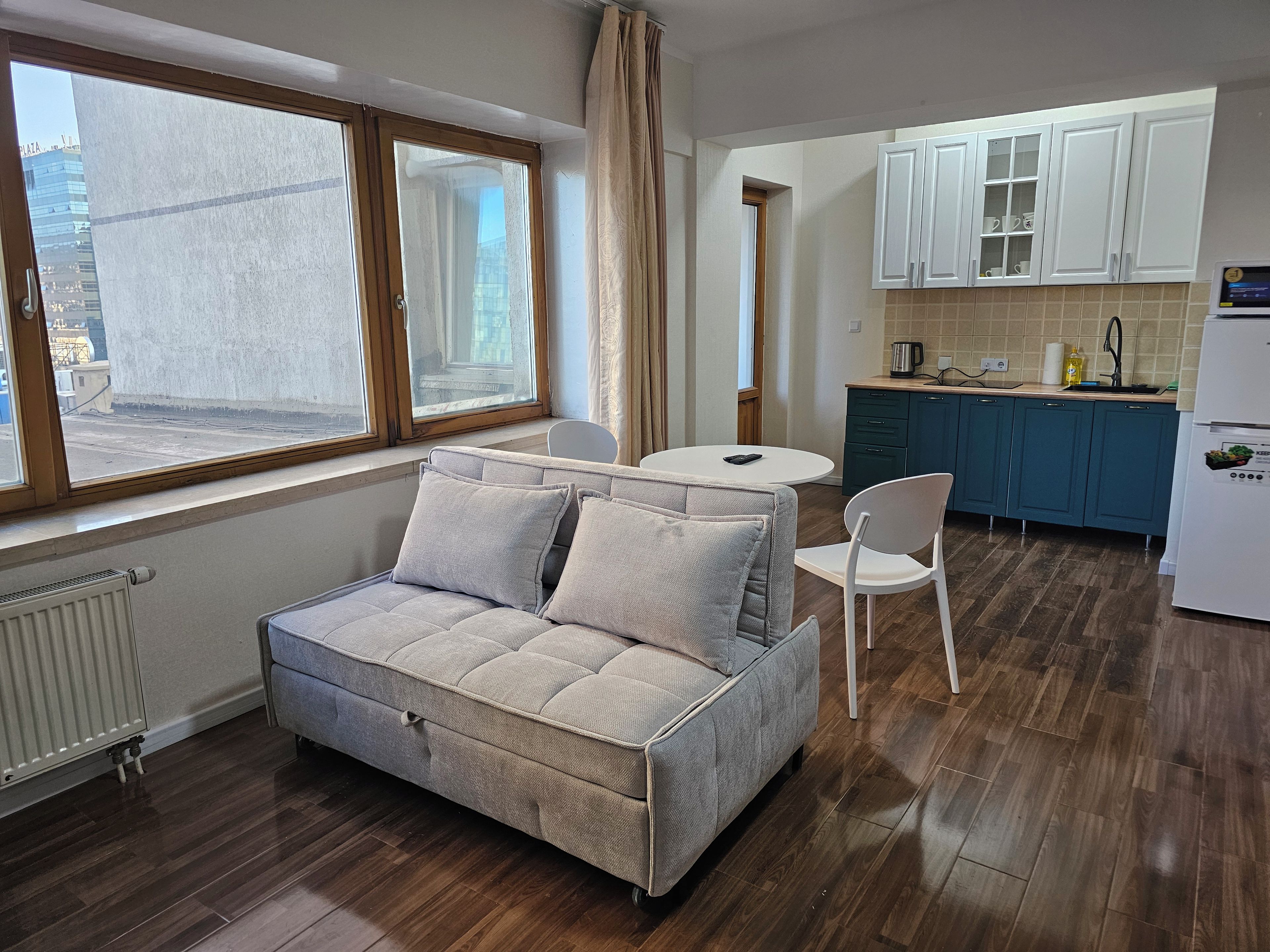 A compact living space with a sofa, a dining table, and a kitchen area.