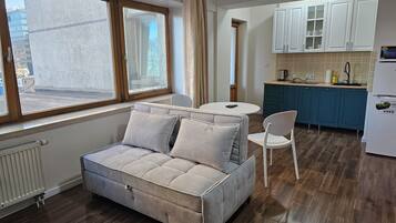 A compact living space with a sofa, a dining table, and a kitchen area.