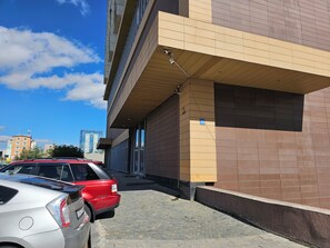 A parking area with a building featuring a tiled facade and a visible address sign. - Max Central City Apartment (Ulaanbaatar)
