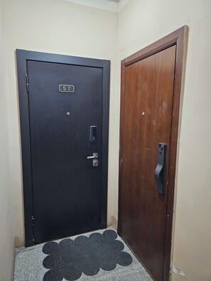 A black door with a numeric keypad and a keyhole, adjacent to a wooden door with a keyhole. - Max Central City Apartment (Ulaanbaatar)