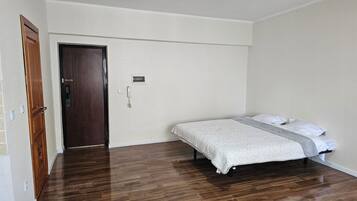 Ein Schlafzimmer mit einem Bett, einer Holztür und einem Lichtschalter an der Wand.