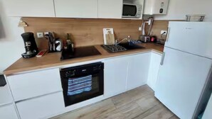 A compact kitchen with white cabinets, a microwave, a dishwasher, and a refrigerator. - Apartment on the 3rd floor, located right in the center of Font-Romeu (Font-Romeu-Odeillo-Via)