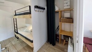 A room with a bunk bed, a shelf with boxes, and a curtain. - Apartment on the 3rd floor, located right in the center of Font-Romeu (Font-Romeu-Odeillo-Via)