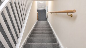 A staircase with a white railing, carpeted steps, and a wooden handrail on the right. - Stylish 3BR House | Free WiFi & Parking | Sleeps 5 | Manchester (Little Hulton)