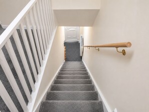 Eine Treppe mit weißer Geländer, Teppichstufen und einem Holzhandlauf auf der rechten Seite.