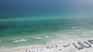 A beach with clear turquoise water, a sandy shore, and numerous umbrellas. - Beach Condo~Steps from Beach~Sleeps 4~Pool~Hot Tub~ (Miramar Beach)