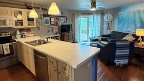 Eine Küche mit Kochinsel, weißen Schränken und einem Essbereich mit Sofa und Lampe.