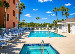 A swimming pool with lounge chairs, a lifeguard tower, and palm trees. - Beach Condo~Steps from Beach~Sleeps 4~Pool~Hot Tub~ (Miramar Beach)