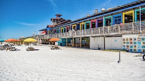 Ein Gebäude direkt am Strand mit farbenfrohen Außenwänden, mehreren Balkonen und Außenbereichen mit Sonnenschirmen.