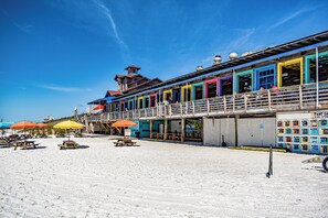 A beachside building with colorful exterior walls, multiple balconies, and outdoor seating areas with umbrellas. - Beach Condo~Steps from Beach~Sleeps 4~Pool~Hot Tub~ (Miramar Beach)