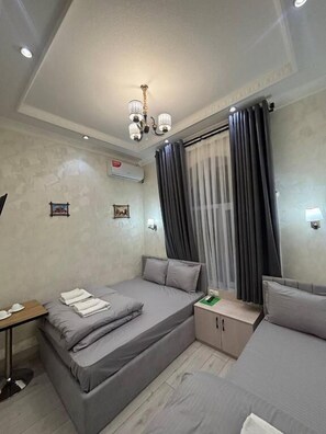 A modern bedroom with a bed, a sofa, a desk, and a chandelier. - GREEN PLAZA (Samarkand)