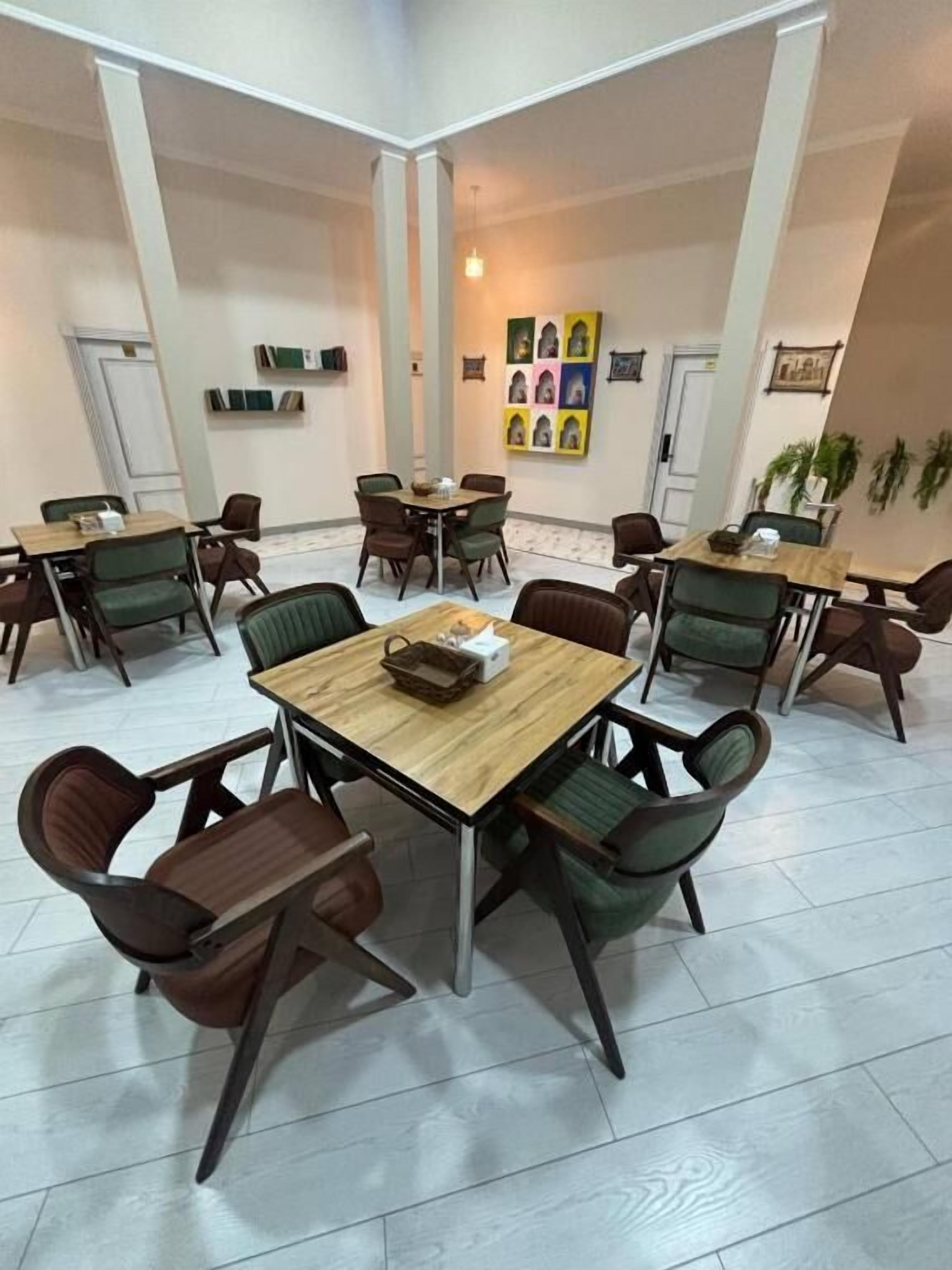 Un salón de conferencias con una mesa y sillas de madera, una pizarra y cuadros en la pared.