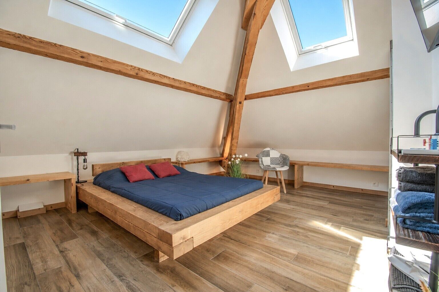 Une chambre à coucher aménagée en mezzanine, avec un lit en bois, des fenêtres de toit et une vue sur le ciel.