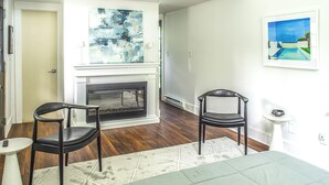 Una habitación con chimenea, dos sillones, una cama y un cuadro en la pared.