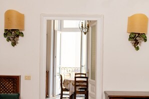 Ein Innenbereich mit einem Flur, einer Tür zu einem Balkon, einer Kristallleuchtre und Wandleuchten.