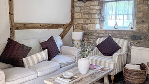 A cozy living room with a sofa, armchair, and coffee table, stone wall, and wooden beams. - Beautiful Cosy 18th Century Cotswold Cottage in Winchcombe (Winchcombe)