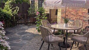 A patio with a table and chairs, surrounded by a stone wall and a wooden fence. - Beautiful Cosy 18th Century Cotswold Cottage in Winchcombe (Winchcombe)