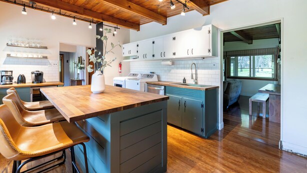 Una cocina moderna con armarios de madera, una isla central con taburetes y vistas al área de comedor.