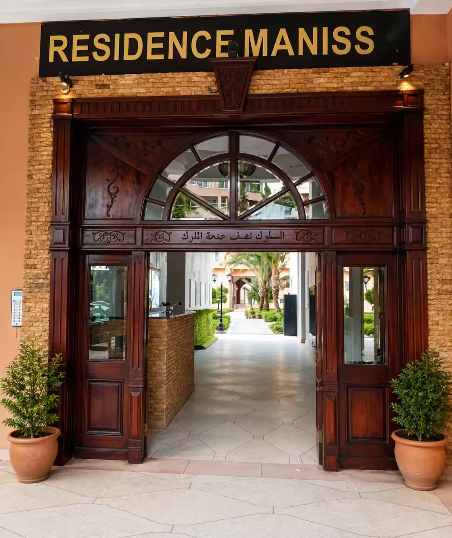 Un acceso imponente con un cartel que dice 'RESIDENCE MANISS' y un arco tradicional.
