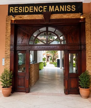 Un acceso imponente con un cartel que dice 'RESIDENCE MANISS' y un arco tradicional.