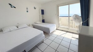 Ett hotellrum med två sängar, en balkong med utsikt och en takfläkt.