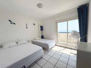 Ein Hotelzimmer mit zwei Betten, einem Balkon und Blick sowie einem Deckenventilator.